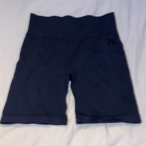 Mörkblå seamless träningsshorts Aim'n - Snygga mörkblå seamless shorts från Aim'n med hög midja och ribbad linning. Perfekta för träning eller chill dagar. Stretchigt material som sitter skönt och följer kroppen. Diskret Aim'n-logga på benet. Passar dig som gillar sportig och clean stil.