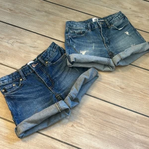 Blå jeansshorts från lager 157, storlek 140 - Snygga blå jeansshorts från 157 med uppvikta benslut. De ena shortsen har slitna detaljer framtill och de andra är helt vanliga. Perfekta för varma dagar och enkel att matcha med allt. Shortsen säljs tillsammans.