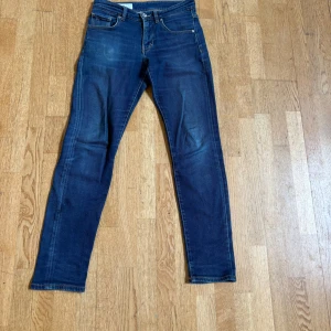 Blå jeans från J.Lindeberg 29/32 - Snygga blå jeans från J.Lindeberg i klassisk femficksmodell. Jeansen har en rak passform med något smalare ben och subtila slitningar för en cool look. Tillverkade i mjukt denimtyg som sitter skönt hela dagen.