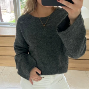 Mörkgrå stickad tröja med öppen rygg - Mysig mörkgrå stickad tröja med oversized passform och vida ärmar. Tröjan har en snygg öppen rygg som ger en cool twist till den annars enkla looken. Perfekt att styla med jeans eller kjol för en trendig vibe. Aldrig använd! Sista bilden är lånad❤️