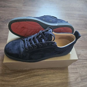 Mörkblå mockasneakers från Christian Louboutin - Snygga mörkblå sneakers från Christian Louboutin i mjuk mocka med klassisk röd sula. Skorna har rund tå, mörkblåa snören och diskreta detaljer. Insidan är i skinn för extra komfort. Perfekta för dig som vill ha en lyxig och stilren look. Hör gärna av er om frågor eller funderingar. Allting og följer med dustbag, äkthetsbevis, box osv. Tvättar skorna innan vi skickar de. Självklart Äkta. MVH Artic resell 