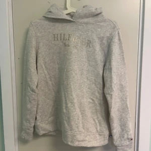 Grå hoodie från Tommy Hilfiger XS - Snygg ljusgrå hoodie från Tommy Hilfiger i storlek XS. Tröjan har huva, lång ärm och diskret logga framtill. Perfekt för dig som gillar en clean och enkel stil. Mjuk bomullskänsla och klassisk passform.