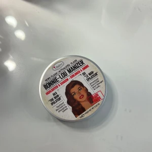 theBalm Bonnie-Lou Manizer highlighter - Bonnie-Lou Manizer från theBalm är en multifunktionell highlighter och ögonskugga i en varm, guldig champagne-nyans. Kommer i en rund, silverfärgad dosa med spegel. Perfekt för att ge glow till både ansikte och ögon.