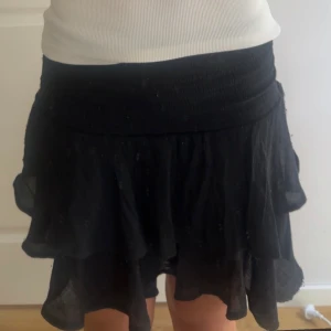 Svart volangkjol med resårmidja - Supersöt svart kortkjol med volanger och bred resår i midjan. 