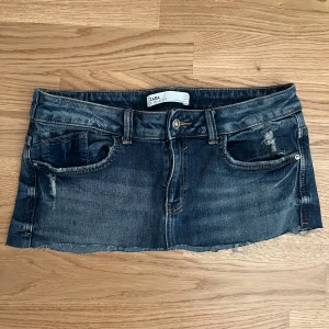 Mörk jeanskjol från ZARA - Superkort jeanskjol från ZARA i mörkblå denim med slitna detaljer och rå kant. Klippte från ett par shorts till en kjol. Den är då inte helt perfekt men är super fin. Säljer då den är väldigt kort på mig💞I kjolen står det att det är storlek 38 men sitter som en 34-36. Kontakta mig för någon minsta fråga💕
