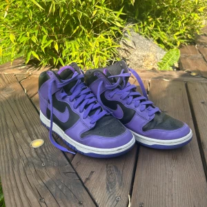 Nike Dunk High svart/lila sneakers - Säljer ett par ”Nike Dunk High Purple Black ”.  STORLEK 40.5  Köpte dem för cirka 1 år sedan, men växte ur dem snabbt. Så knappast använda!  Köpte dem för 1699kr och därför säljer dem för 799kr. ❗️PRIS GÅR FÖRHANDLAS ❗️