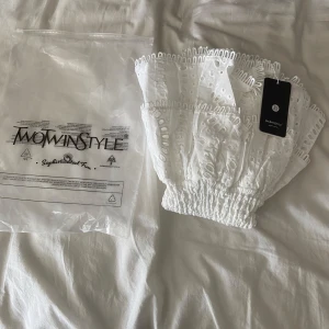 Vit kort klänning från MotwinStyle - Supersöt vit kort klänning från MotwinStyle med smockad överdel och volangig kjol🤍. Klänningen har broderade detaljer och är ärmlös, perfekt för sommarens alla tillfällen. Materialet känns lätt och luftigt, och den har en riktigt fräsch vibe. Den är ALDRIG använd!