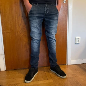 Dondup jeans - Säljer ett par mörkblå jeans från Don dup med snyggt slitna detaljer och klassisk femficksdesign. Jeansen har en tapered passform och normal midja. Materialet är stretchigt jeans för extra komfort. Perfekt för dig som gillar en modern och avslappnad stil. Det finns ingen storlek i jeansen så skulle gissa på 28/31
