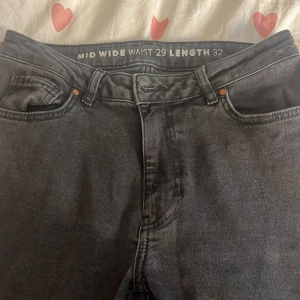 Svarta wide jeans midwaist W29 L32 - Säljer ett par svarta jeans med midwaist och wide fit. Klassisk femficksmodell med dragkedja och knapp. Snygg tvättad svart färg och raka, breda ben som ger en chill vibe. Perfekta till sneakers eller boots. Ca strl M