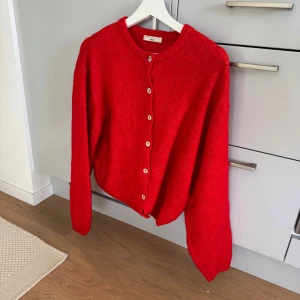 Röd kofta från Gina Tricot - Superfin röd kofta från Gina Tricot och deras premium collection med rund halsringning och snygga knappar framtill. Koftan är stickad och har långa ärmar. 