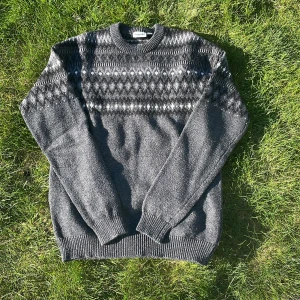 Mörkgrå stickad tröja med mönster från Kappahl - Säljer en mörkgrå stickad tröja från Kappahl med vitt och ljusgrått mönster över bröstet och axlarna. Tröjan har rund halsringning och långa ärmar. Perfekt för kyliga dagar!