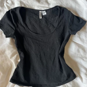 Svart kortärmad topp från hm - En enkel svart topp från hm med rundad urringning och korta ärmar. Perfekt basplagg att matcha med olika outfits. Tillverkad i mjukt bomullsmaterial.