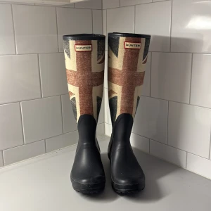 Coola Hunter stövlar med Union Jack-mönster❤️ - Säljer ett par höga Hunter stövlar med Union Jack-flaggan.  Stövlarna är svarta nedtill och har ett klassiskt Hunter-märke framtill. För små för mig så jag måste sälja dem tyvärr. 