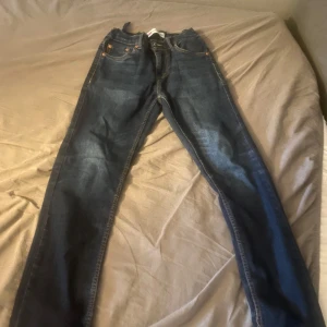 Levi's 512 Slim Taper jeans - Mörkblå Levi's 512 Slim Taper jeans med klassiska fem fickor och orange sömmar. Byxorna har en slim passform som smalnar av nedtill och är tillverkade i jeansmaterial. Perfekta för dig som gillar en modern och stilren look. Nypris 700kr