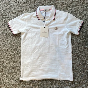 Moncler pike - En helt ny Vit moncler piké. Den har inga skador. Det står L men passar som M eftersom moncler storlekar är jätte konstiga.