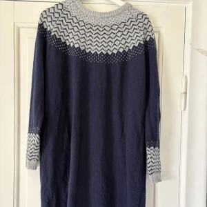 Stickad klänning från Holly & Whyte by Lindex - Mysig stickad klänning i marinblått med ljusgrått mönster upptill och på ärmarna. Långärmad och perfekt för kyligare dagar. Rund halsringning och klassiskt nordiskt mönster. Nästintill oanvänd.