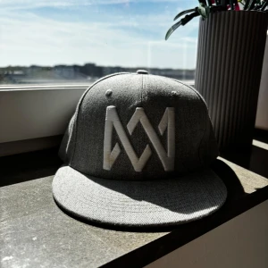Grå keps Marcus & Martinus - Snygg grå keps med stort broderat M&M-logo framtill och texten 'Marcus & Martinus' baktill. Finns en liten fläck på loggan som visas på bilden. Skriv gärna innan ni trycker på köp🫶🏻