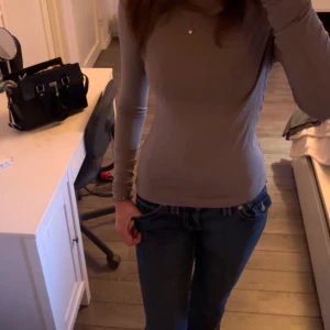 Grå långärmad topp - Säljer en enkel och stilren grå långärmad topp med tight passform. Perfekt att matcha med jeans eller kjol för en clean look. Mjuk och skön mot huden.