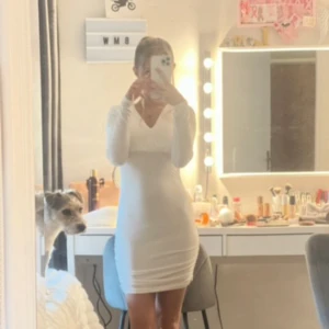 Vit tight kortklänning med v-ringning - Säljer en vit tight kortklänning med v-ringning och långa ärmar. Klänningen har en enkel och stilren design som framhäver figuren. Perfekt för dig som gillar minimalistisk stil.