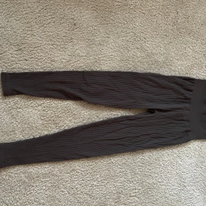 Gråa ribbade leggings - Säljer ett par gråa leggings med ribbad struktur. De har en tight passform och är perfekta för en avslappnad stil eller till träning. Materialet är stretchigt och bekvämt.