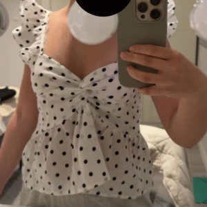 Vit prickig blus med volangärmar - Supersöt vit blus med svarta prickar och volangärmar. .