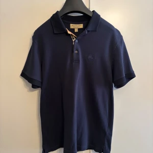 Burberry piké  - Säljer en mörkblå Burberry piké som är mycket bra skick. Den är äkta och är köpt från Farfetch. Finns även kvitto!