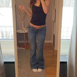 Lågmidjade bootcut jeans - Säljer ett par klassiska blå bootcut jeans med låg midja. Jeansen har en snygg passform som sitter tight upptill och släpper ut vid benen. 