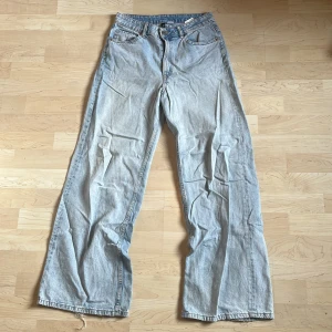 Ljusblå wide jeans från H&M - Säljer ett par ljusblå jeans från H&M med breda ben och klassisk femficksdesign. Jeansen har hög midja och raka, vida ben för en avslappnad look. Perfekta för dig som gillar en trendig och bekväm stil.