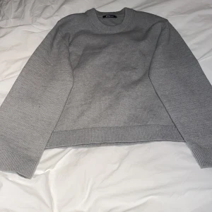 Grå stickad tröja från Gina Tricot - Säljer en enkel och stilren grå stickad tröja från Gina Tricot i storlek XS. Tröjan har rund halsringning, långa ärmar och ribbade muddar vid ärmslut och nederkant. Perfekt basplagg till garderoben. Stor i storlek 