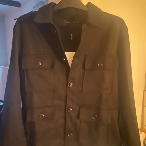 Svart skön overshirt från Brand Island - Säljer en svart overshirt från Brand Island sprillans ny helt oanvänd med lappen kvar. perfekt för lager-på-lager. Enkel och stilren design som passar till mycket. Strl M men passar även strl L