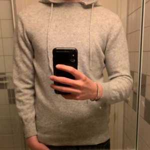 Ljusgrå hoodie - Säljer en stilren kashmir tröja som har okänt märke har ingen lapp eller något som visar vart den är ifrån men den är fin och är lite sönder i kragen endast
