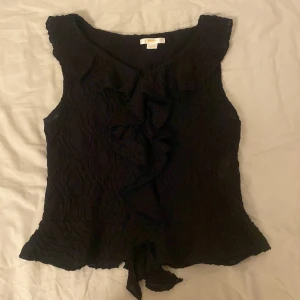 Svart volangprydd ärmlös topp från Gina Tricot - Säljer en svart ärmlös topp från Gina Tricot med volangdetaljer framtill. Toppen passar storlekarna xs och s ❤️
