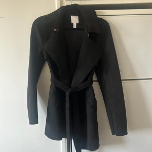Svart kappa med bälte från H&M - Säljer en svart kappa från H&M i storlek XS. Jackan har långa ärmar, bred krage och knyts med bälte i midjan och har två fickor!  Finns i Kristinehamn och kan skickas mot fraktkostnad eller mötas upp🤍