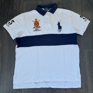 Ralph Lauren piké vit och blå - En riktigt fräsch Ralph Lauren piké som nästan är helt oanvänd och väldigt bra skick med speciell design! Märke • Ralph Lauren  Skick • 10/10 Storlek • XL Modell • Slim fit big pony polo Färg • Vit och marinblå Frakt • skickas samma dag eller dagen efter köp