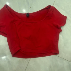 Röd croppad topp från SHEIN - Säljer en röd croppad topp från SHEIN med korta ärmar och bred urringning. Perfekt för dig som vill ha en enkel men snygg topp till sommaren. Toppens material känns mjukt och stretchigt.