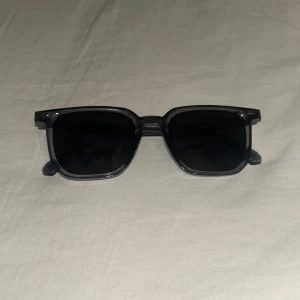 Svarta solglasögon med fyrkantig båge - Snygga svarta solglasögon med fyrkantig båge och mörka linser. Klassisk och stilren design som passar till många olika outfits. Bågarna är i plast och har en modern känsla.