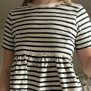 Randig topp från Zara - Säljer en vit och marinblå randig topp från Zara med kort ärm och lös passform. Toppen har en volang nedtill som ger en söt och avslappnad look❤️‍🔥använd ett fåtal gånger. Passar till allt❤️‍🔥tror inte den finns att köpa hos zara längre så ta chansen💫