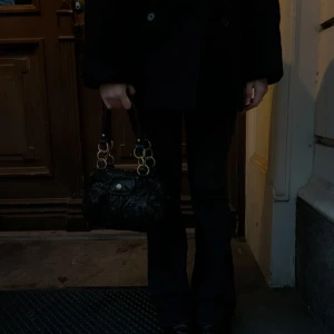 Svart handväska med ormmönster och gulddetaljer - Säljer en svart handväska med ormmönster och snygga guldfärgade ringdetaljer på handtagen. Väskan har ett lock med knappstängning och är tillverkad i skinnliknande material. Perfekt storlek, rymlig och supersnygg!!💕💕💕