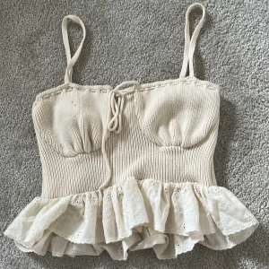 Beige stickad linnetopp med volang från Zara - Supersöt beige stickad linnetopp från Zara med smala axelband och volangkant i spets nertill. Toppen har knytning framtill. Storlek M men liten u storlek så passar mig som är XS-XXS😊 pris är diskuterbart.