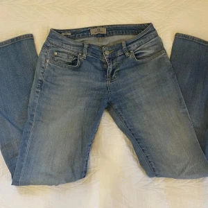 lågmidjade LTB jeans - Säljer ett par ljusblå jeans från LTB med klassisk femficksdesign och mörkblå broderad detalj på bakfickorna. Jeansen har normal passform och raka ben, perfekt för en avslappnad stil.