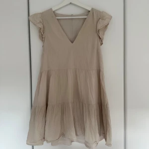 Beige volangklänning med v-ringning - Supersöt beige klänning från h&m, med vi ringning och volang ärmar. 