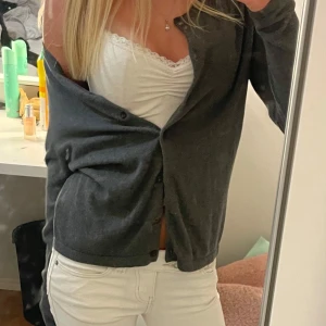 Mörkgrå kofta med knappar - Mysig mörkgrå kofta med knäppning framtill. Koftan har en enkel och stilren design med långa ärmar och normal passform. Perfekt att slänga över en topp för en chill look. Tillverkad i mjukt material som känns skönt mot huden. Kontakta mig för fler bilder eller frågor!