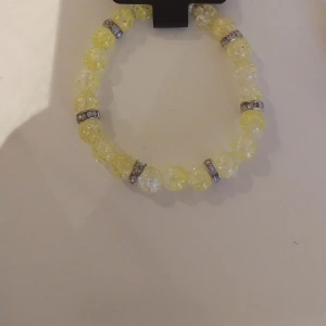 Gult pärlarmband med glittriga detaljer - Snyggt armband med gula och transparenta pärlor, varvat med glittriga silverfärgade mellanringar. Pärlorna är facetterade och ger ett coolt skimmer. Perfekt accessoar för att liva upp din outfit.