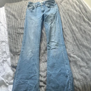 Bootcut jeans från ONLY i ljusblå denim - Bootcut jeans från ONLY i ljusblå denim med klassisk femficksdesign och normal passform. Jeansen har utsvängda ben och snyggt slitna detaljer vid bensluten. Det är storlek 32 på jeansen så skulle nog säga att de passar för folk som bär från Xss till S då de är stretchiga. Köpta för 550 men säljs för 100