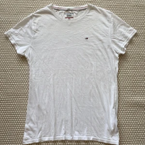 Vit t-shirt från Tommy Hilfiger - Klassisk vit t-shirt från Tommy Hilfiger med liten broderad logga på bröstet. Lite skrynklig på bilden men annars fin och i ok skick.