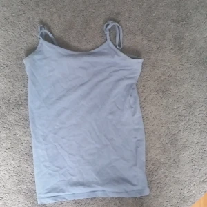 Ljusblå linnetopp från XOXO friends - Säljer en enkel och stilren ljusblå linnetopp från XOXO friends. Toppen har smala axelband och är tillverkad i mjuk bomull, perfekt för varma dagar. Passformen är normal och toppen är ärmlös för en avslappnad look.