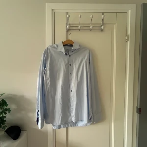 Ljusblå klassisk skjorta - Snygg ljusblå skjorta från Stenströms med klassisk krage och långa ärmar. Skjortan har knappar framtill och är tillverkad i bomull, perfekt för en clean och stilren look.