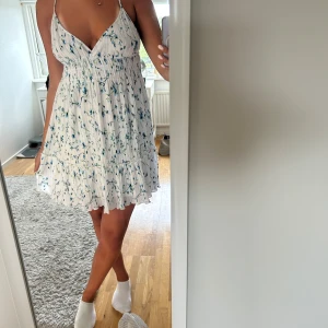 Vit blommig kortklänning  - Supersöt vit kortklänning med justerbara axelband. Den är köpt från Gina Tricot och är i storlek L. Hör av dig vid frågor🤍