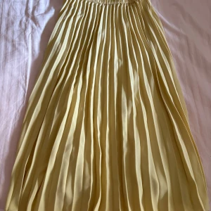 Gul plisserad midikjol - Superfin gul plisserad midikjol från Gina tricot i storlek 36. Kjolen har elastisk midja och snygga veck som ger ett flowy intryck. Perfekt för dig som vill sticka ut med en färgglad look i sommar eller vår.