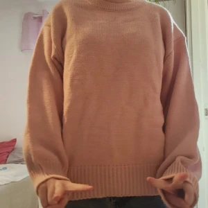 Ljusrosa stickad tröja - Supermysig ljusrosa stickad tröja. Tröjan har en klassisk rund halsringning, ribbade muddar och nederkant samt långärmade ärmar. Perfekt för lager på lager och chill dagar. Passar dig som gillar en enkel men söt stil.